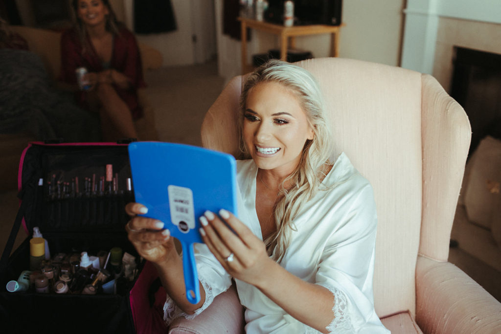 bride checks her makeup in a small handheld mirror