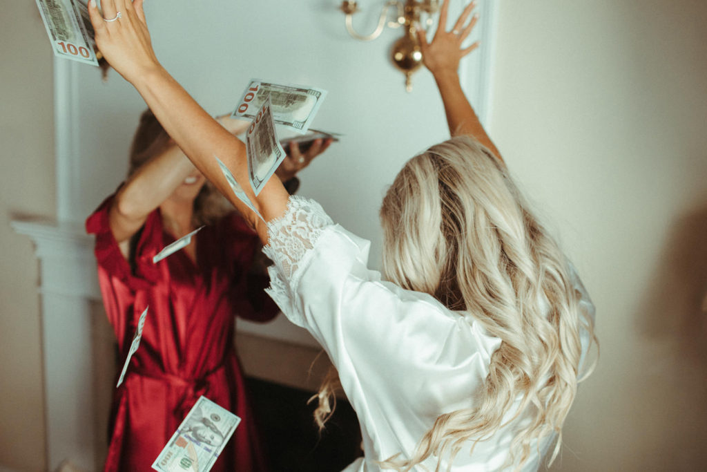 bride is showered with dollar bills by a bridesmaid