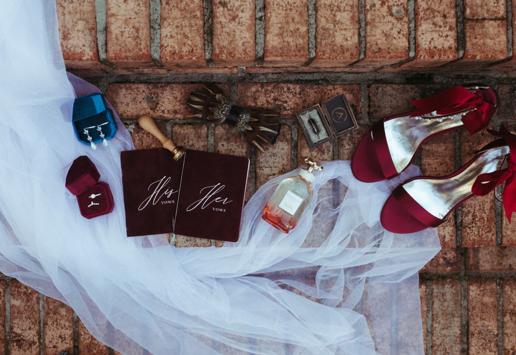 bride and groom detail photo of the vow books, shoes, perfume and veil on stairs