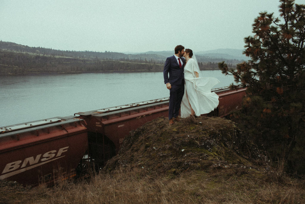 couple posing by a train in the columbia river gorge after having an intimate elopement