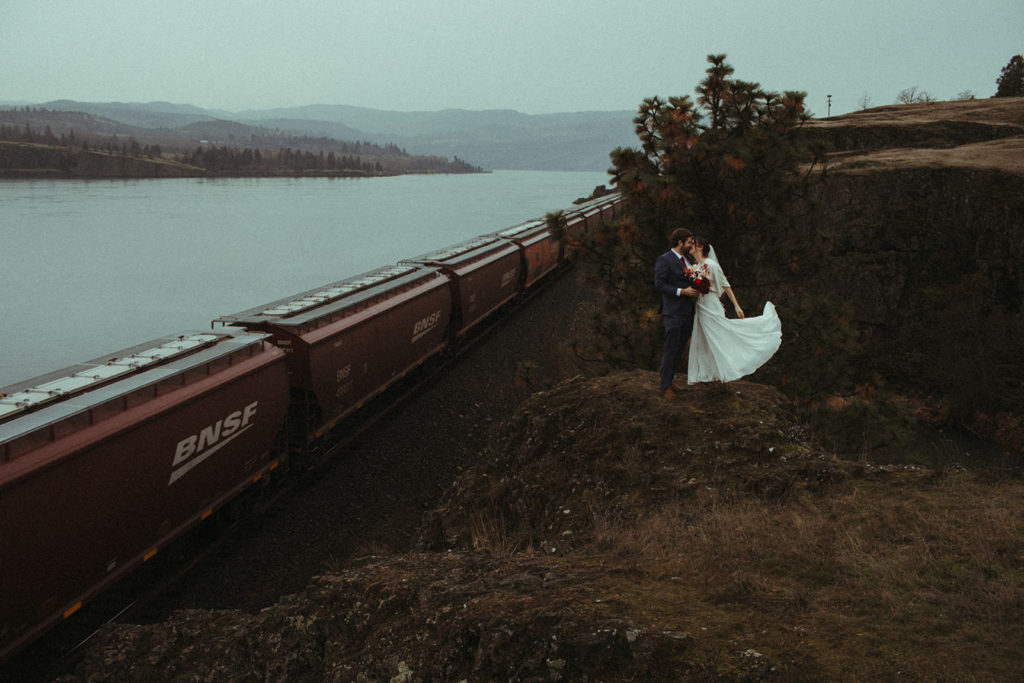 couple posing by a train in the columbia river gorge after having an intimate elopement
