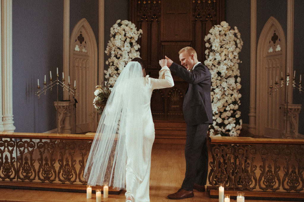 groom helps his bride up the stairs at the academy chapel